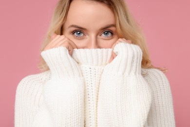 Beautiful woman in stylish warm sweater on pink background