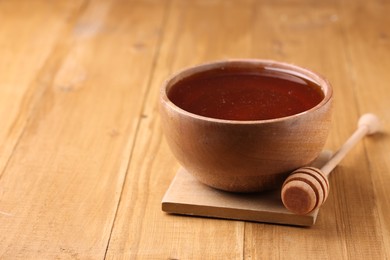 Photo of Delicious honey in bowl and dipper on wooden table. Space for text