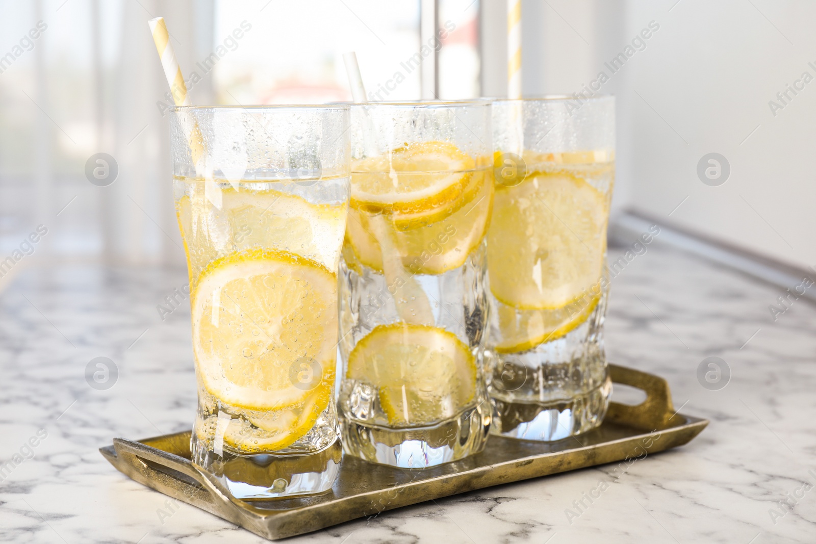 Photo of Soda water with lemon slices on white marble table