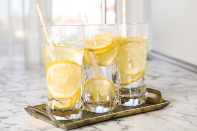 Photo of Soda water with lemon slices on white marble table