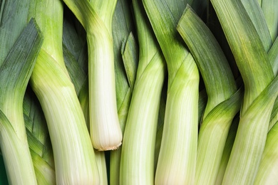 Fresh raw leeks as background, closeup. Ripe onion