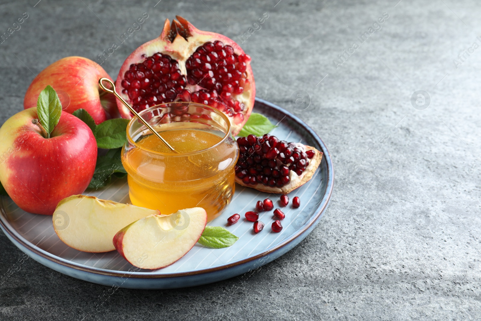 Photo of Honey, pomegranate and apples on grey table. Rosh Hashana holiday