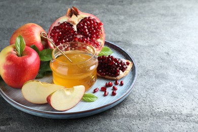 Photo of Honey, pomegranate and apples on grey table. Rosh Hashana holiday