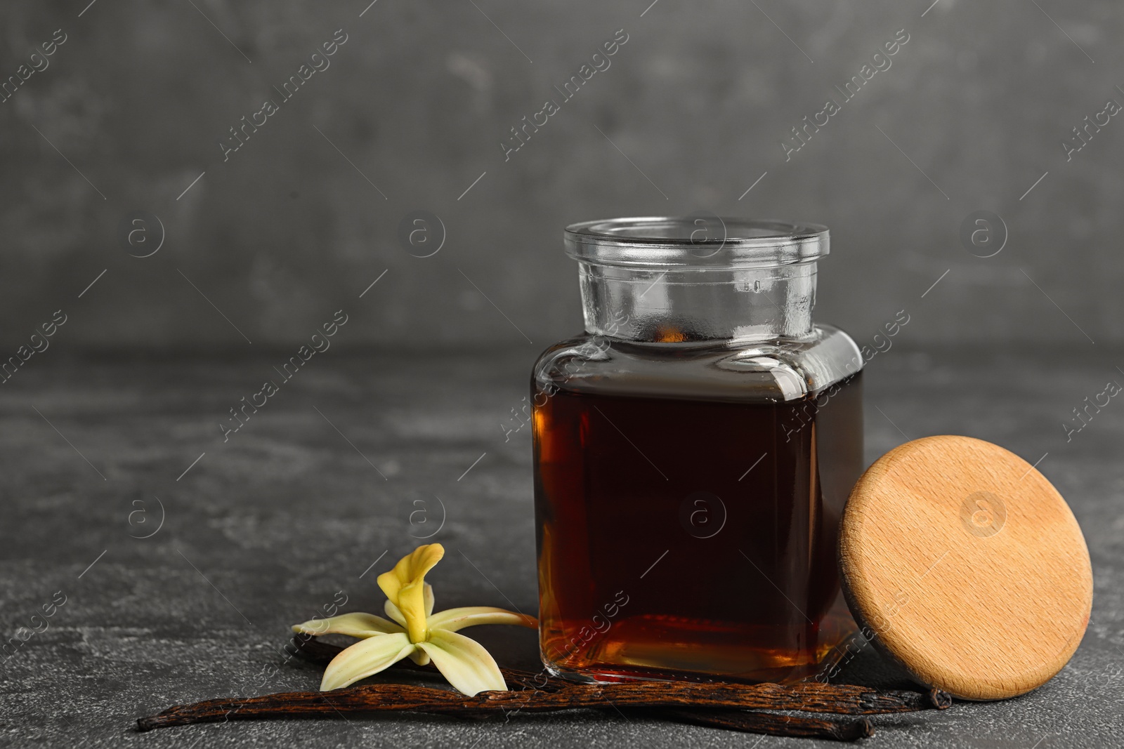 Photo of Aromatic homemade vanilla extract on grey table