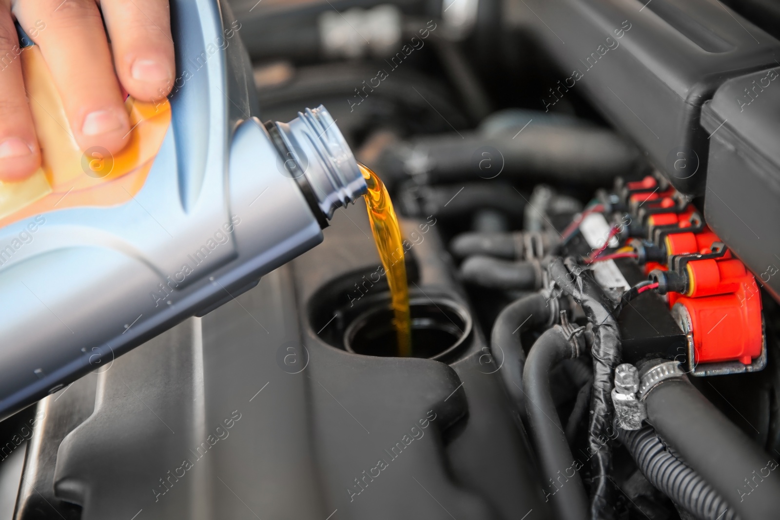 Photo of Mechanic pouring oil into car engine, closeup