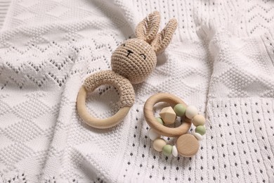 Photo of Baby accessories. Rattle and teether on white knitted fabric