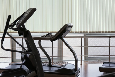 Photo of Elliptical trainer and treadmill in gym. Modern sport equipment
