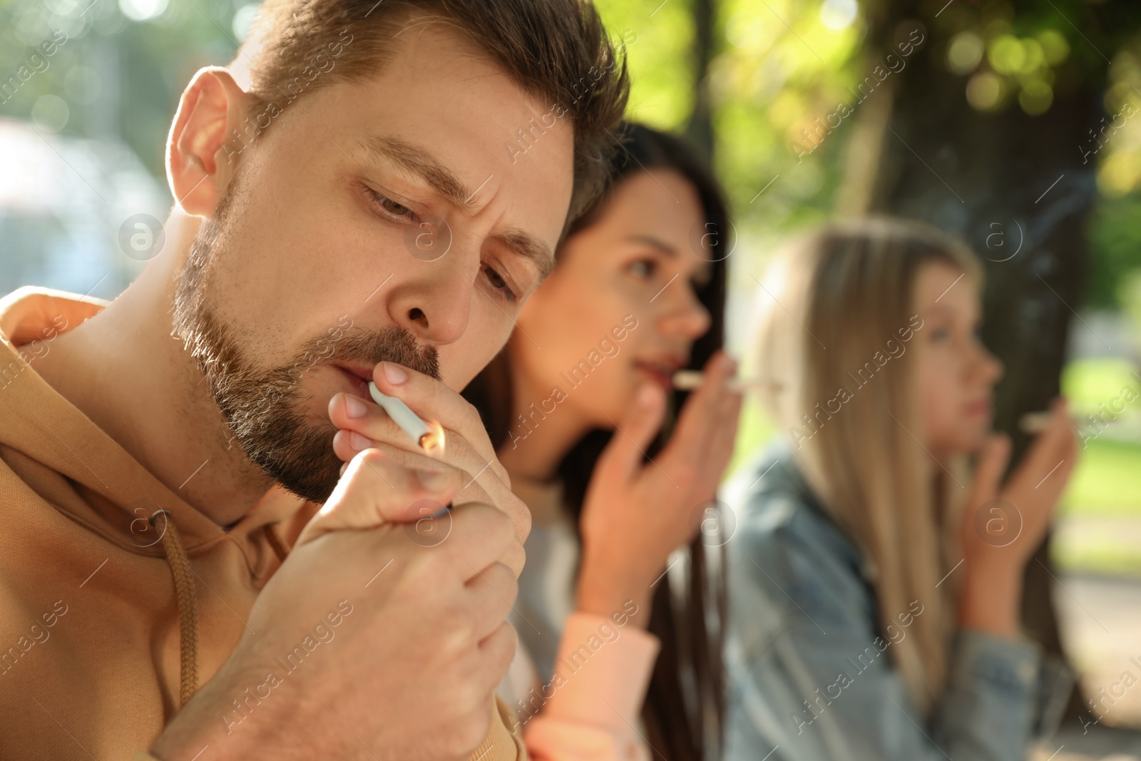 Photo of People smoking cigarettes outdoors on sunny day