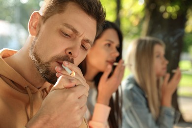 Photo of People smoking cigarettes outdoors on sunny day
