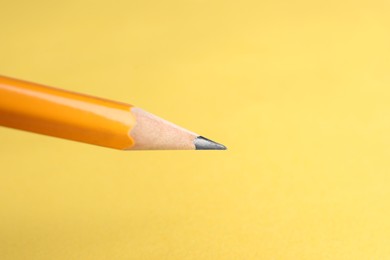 One sharp graphite pencil on yellow background, closeup. Space for text