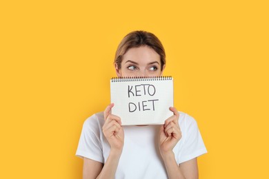 Photo of Woman holding notebook with phrase Keto Diet on yellow background
