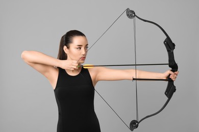 Young woman practicing archery on light grey background