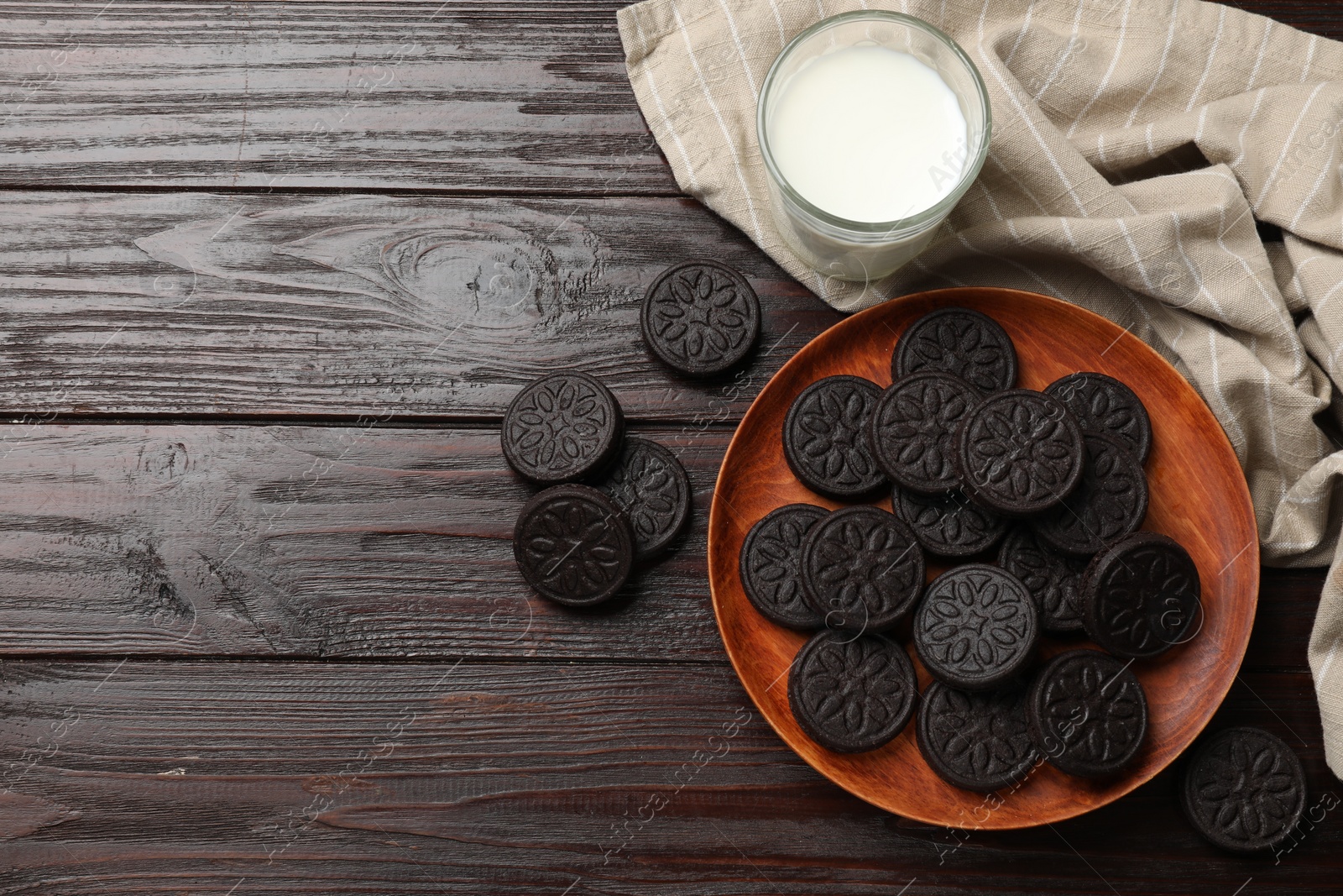 Photo of Plate with tasty sandwich cookies and milk on wooden table, flat lay. Space for text