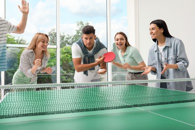 Photo of Happy friends playing ping pong together indoors