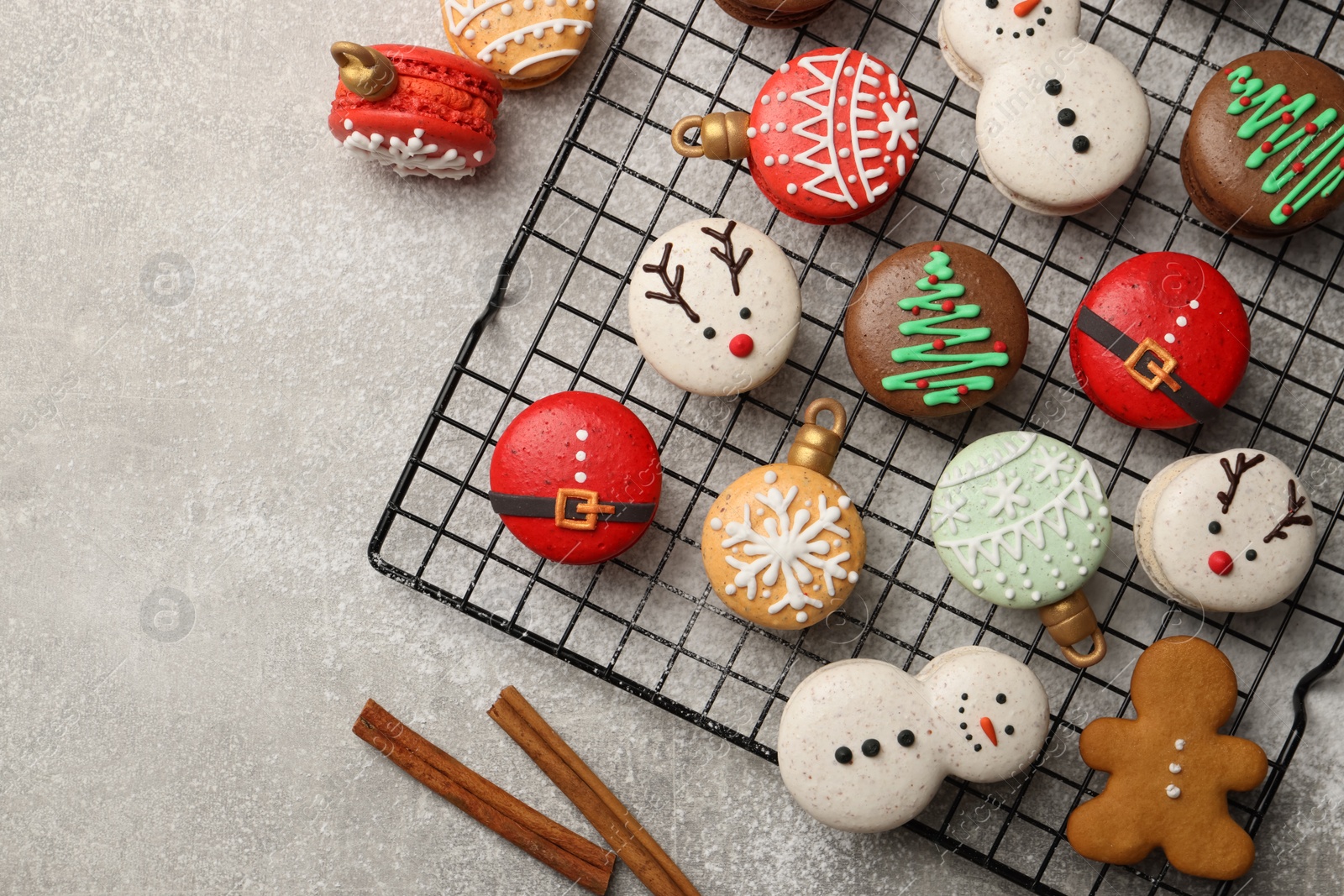 Photo of Beautifully decorated Christmas macarons and cinnamon on light grey table, flat lay