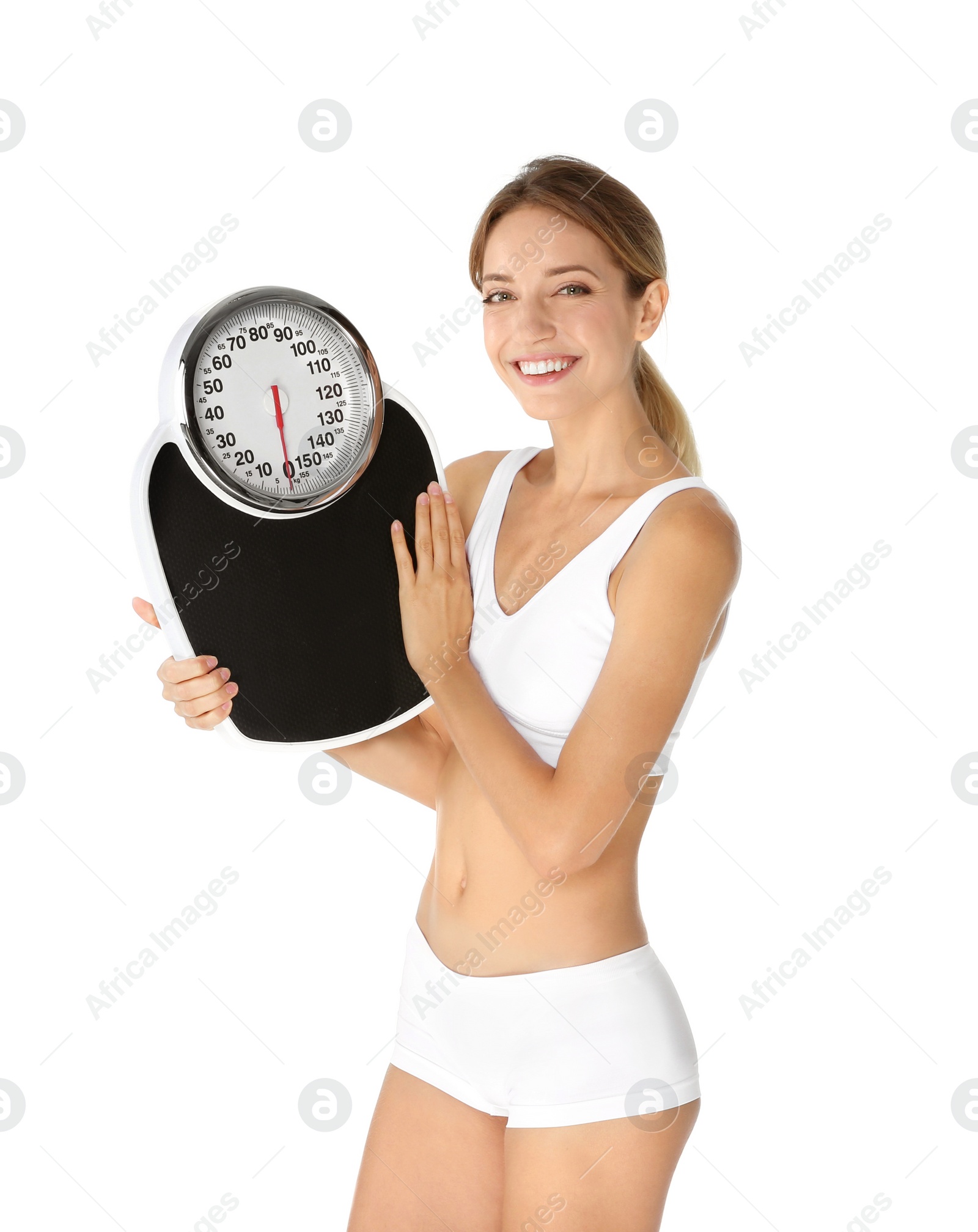 Photo of Happy slim woman satisfied with her diet results holding bathroom scales on white background