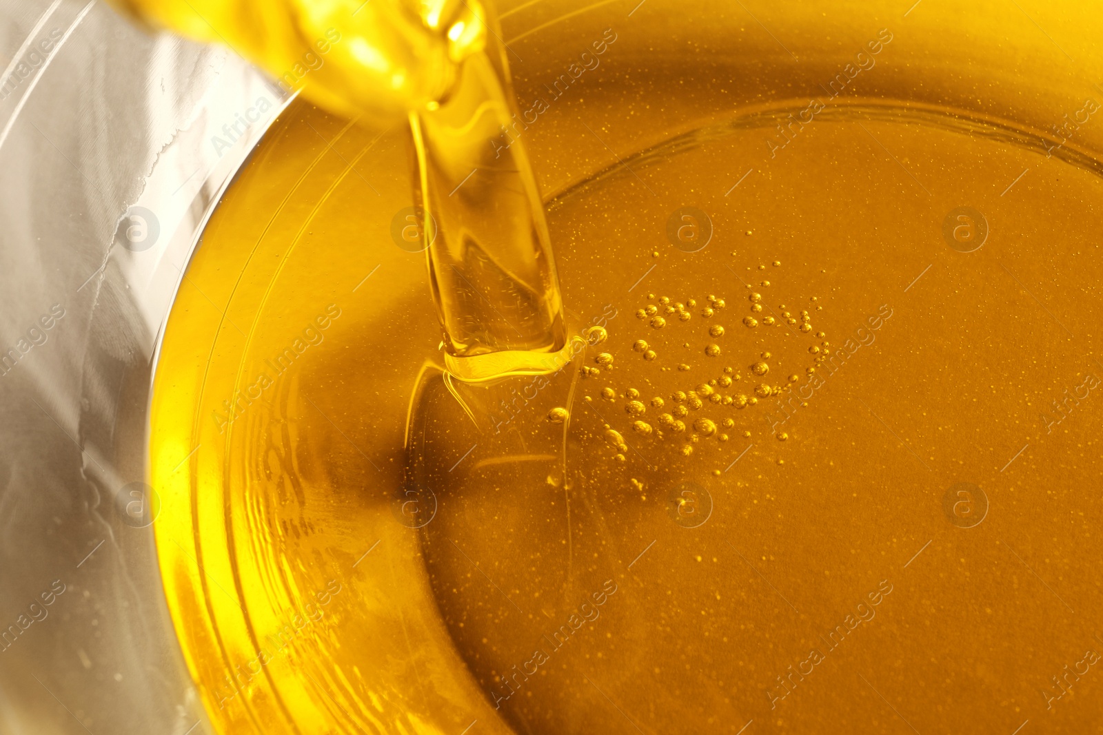 Photo of Pouring cooking oil into bowl, closeup view