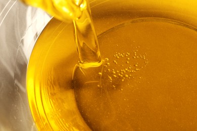 Pouring cooking oil into bowl, closeup view