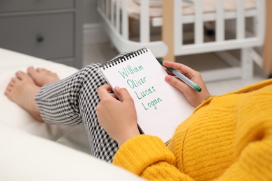 Photo of Pregnant woman with baby names list sitting on sofa, closeup