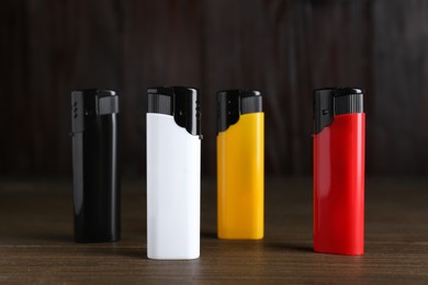 Photo of Stylish small pocket lighters on wooden table