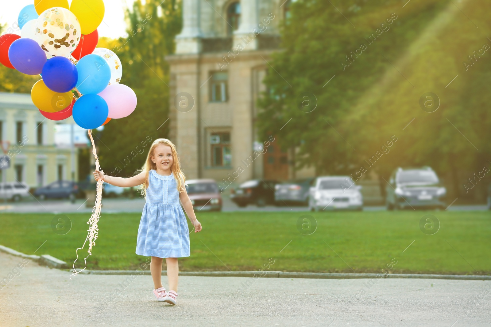 Photo of Little girl with colorful balloons outdoors on sunny day