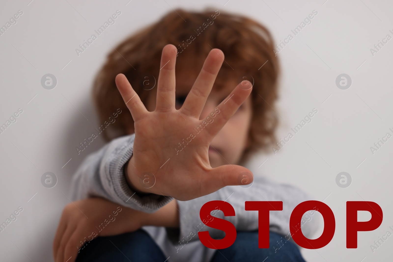 Image of No child abuse. Boy making stop gesture near white wall, selective focus