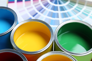 Photo of Paint cans and color palette samples on table, closeup