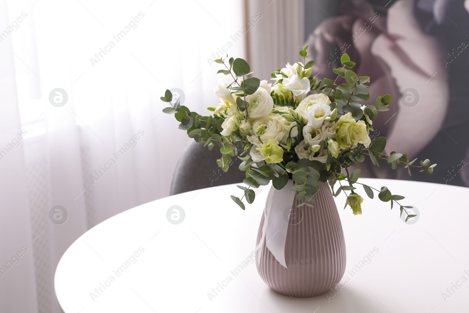 Photo of Vase with beautiful bouquet on white table indoors. Stylish interior element