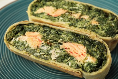 Pieces of delicious strudel with salmon and spinach on plate, closeup
