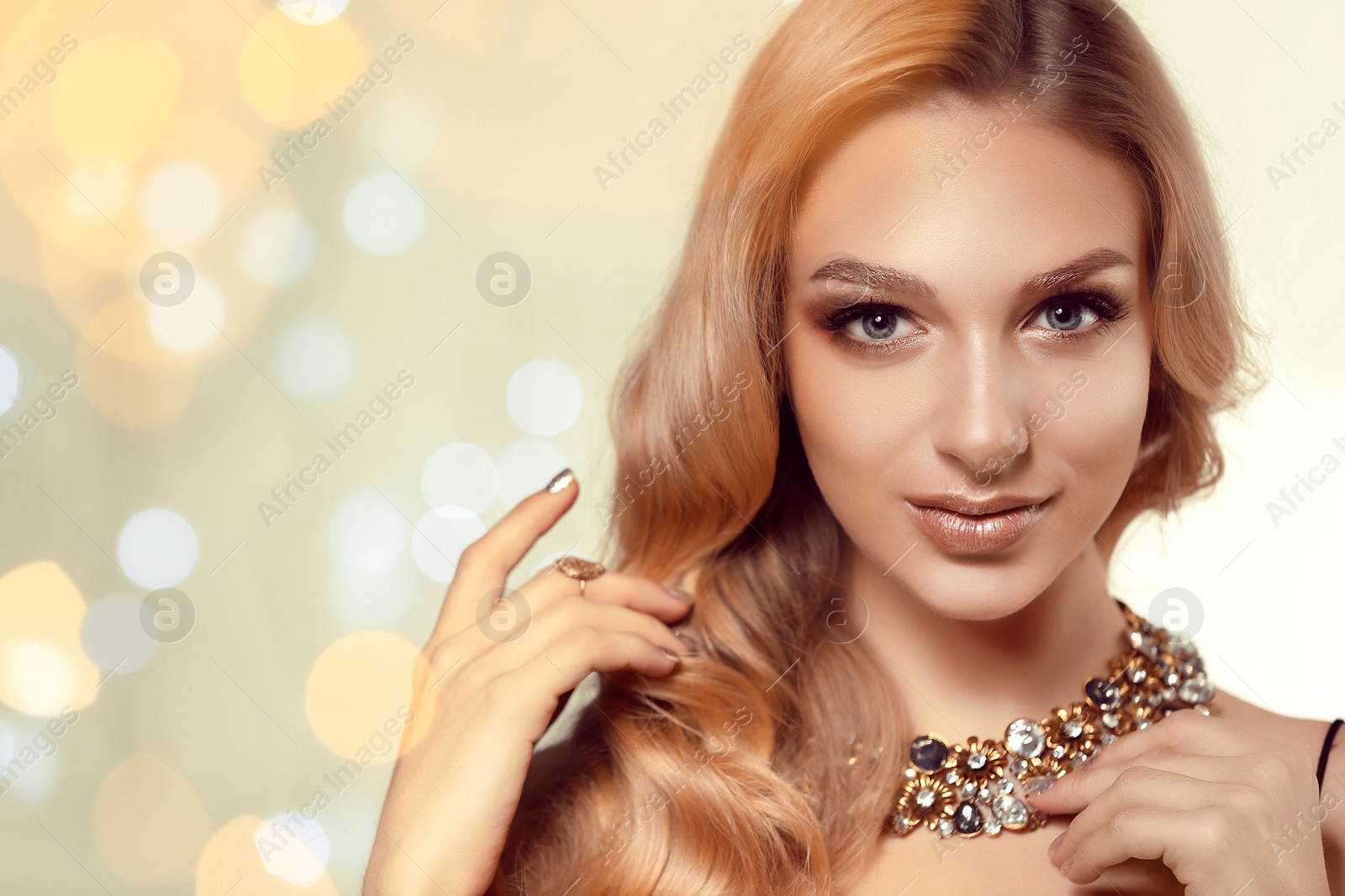 Photo of Beautiful young woman with elegant jewelry against defocused lights. Space for text