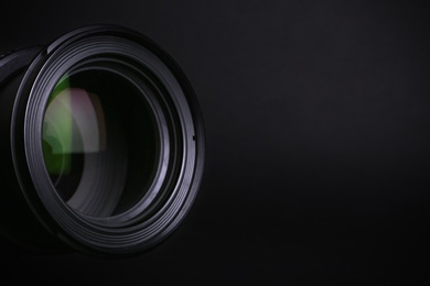 Modern camera lens on black background, closeup. Space for text