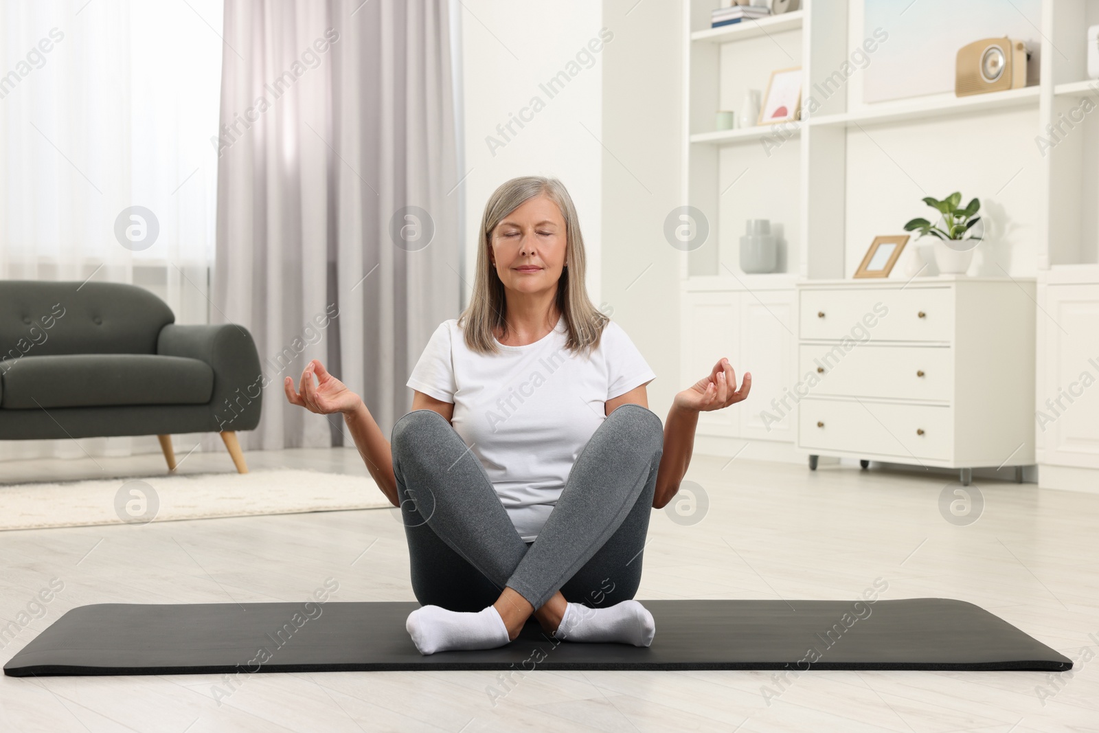 Photo of Senior woman practicing yoga on mat at home