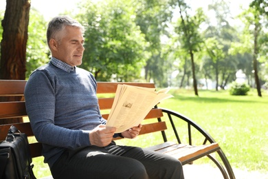 Photo of Portrait of handsome man reading newspaper in park, space for text