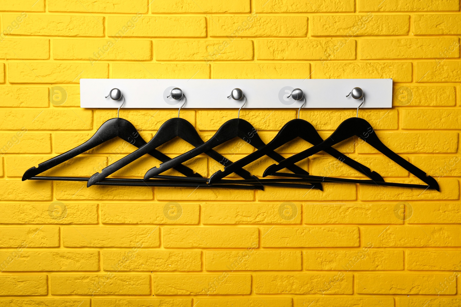 Photo of Rack with clothes hangers on yellow brick wall