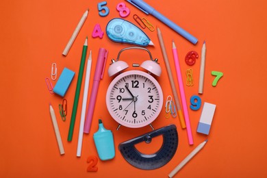 Photo of Flat lay composition with different school stationery and alarm clock on red background. Back to school