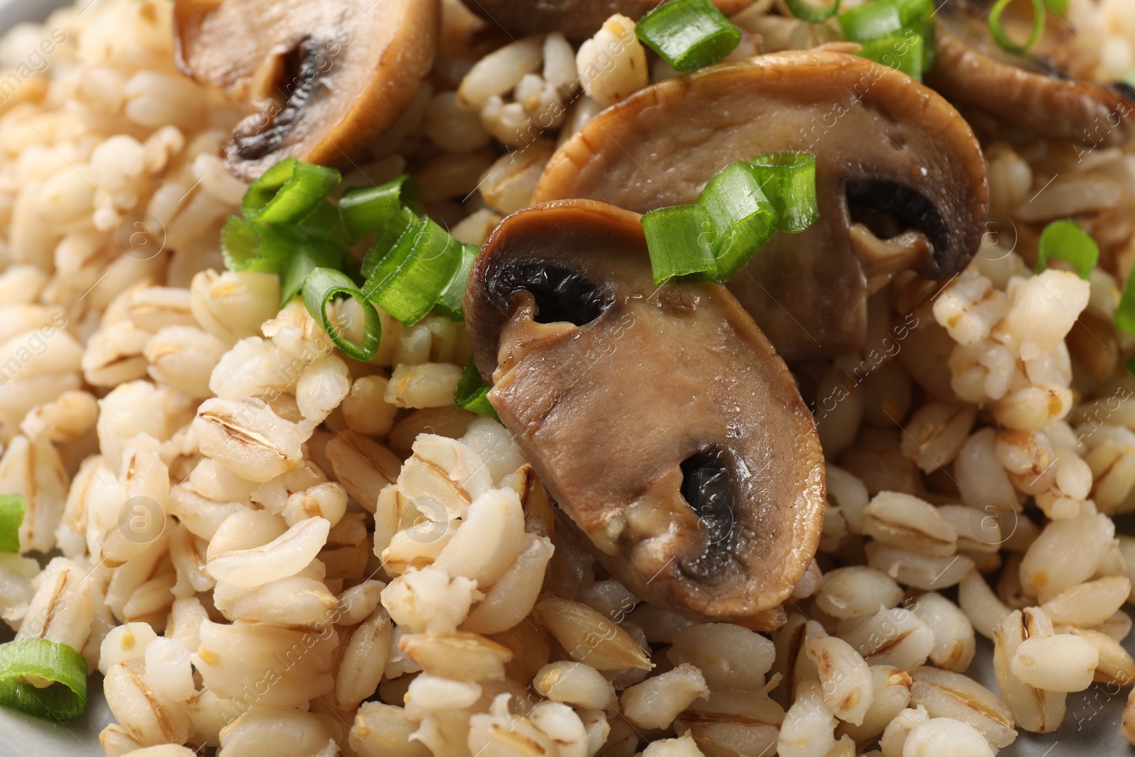 Photo of Delicious pearl barley with onion and mushrooms as background, closeup