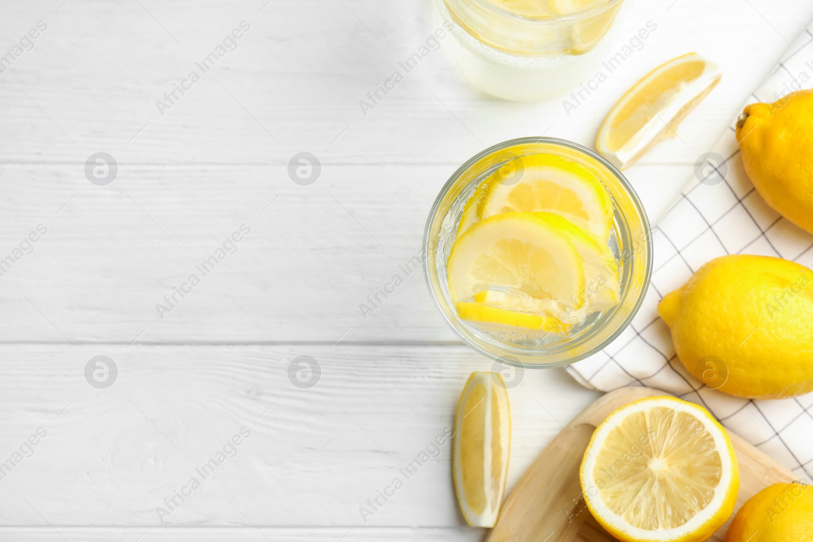 Photo of Soda water with lemon slices and fresh fruits on white wooden table, flat lay. Space for text