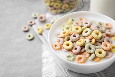 Photo of Tasty colorful cereal rings and milk in bowl on grey table, closeup. Space for text