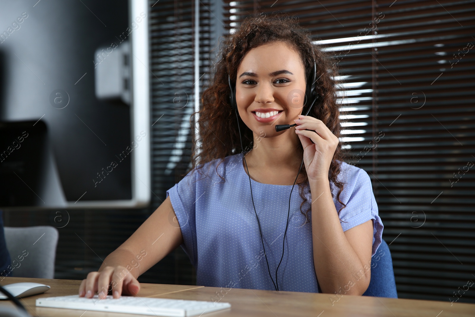 Photo of African-American technical support operator with headset at workplace