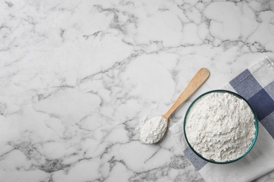 Bowl and spoon with wheat flour on marble background