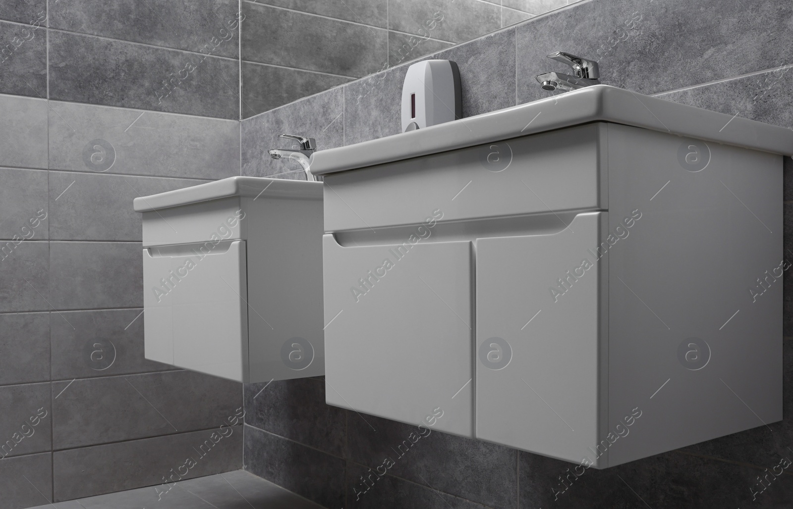Photo of Public toilet interior with stylish white sinks and grey tiles