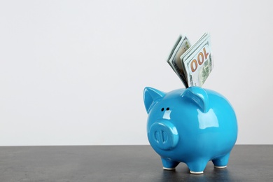 Photo of Piggy bank with dollar banknotes on table against white background. Space for text