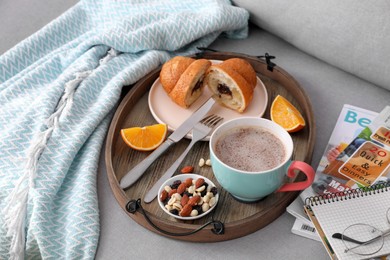 Photo of Tray with tasty breakfast on grey sofa in morning