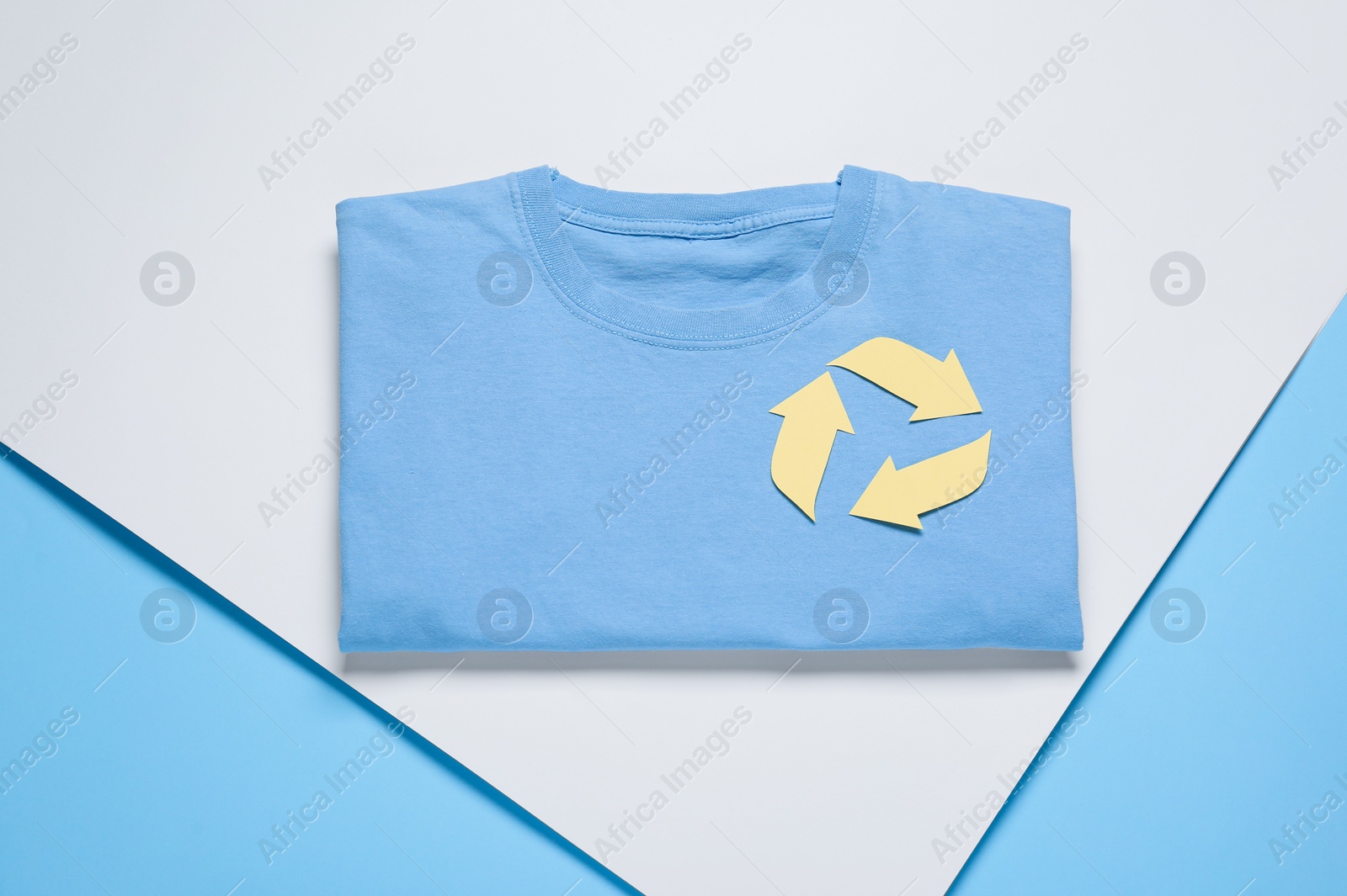 Photo of Shirt with recycling symbol on color background, top view