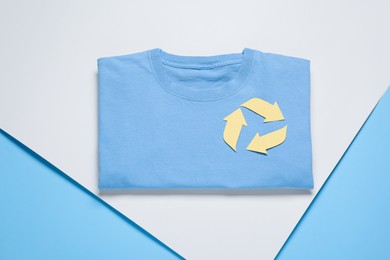 Photo of Shirt with recycling symbol on color background, top view