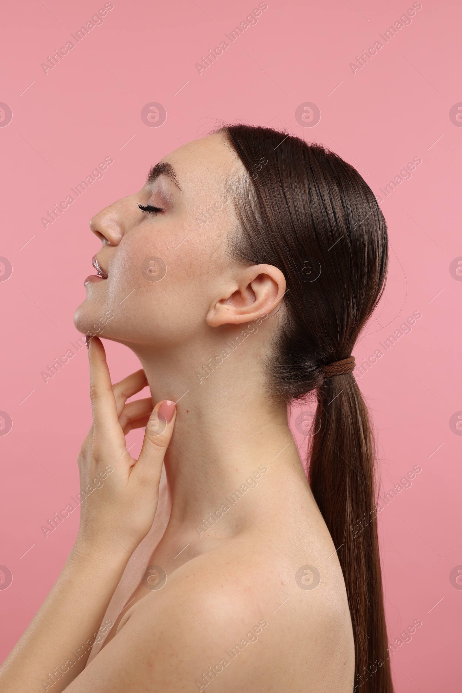 Photo of Beautiful woman touching her chin on pink background