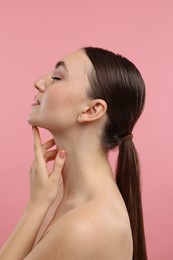 Beautiful woman touching her chin on pink background