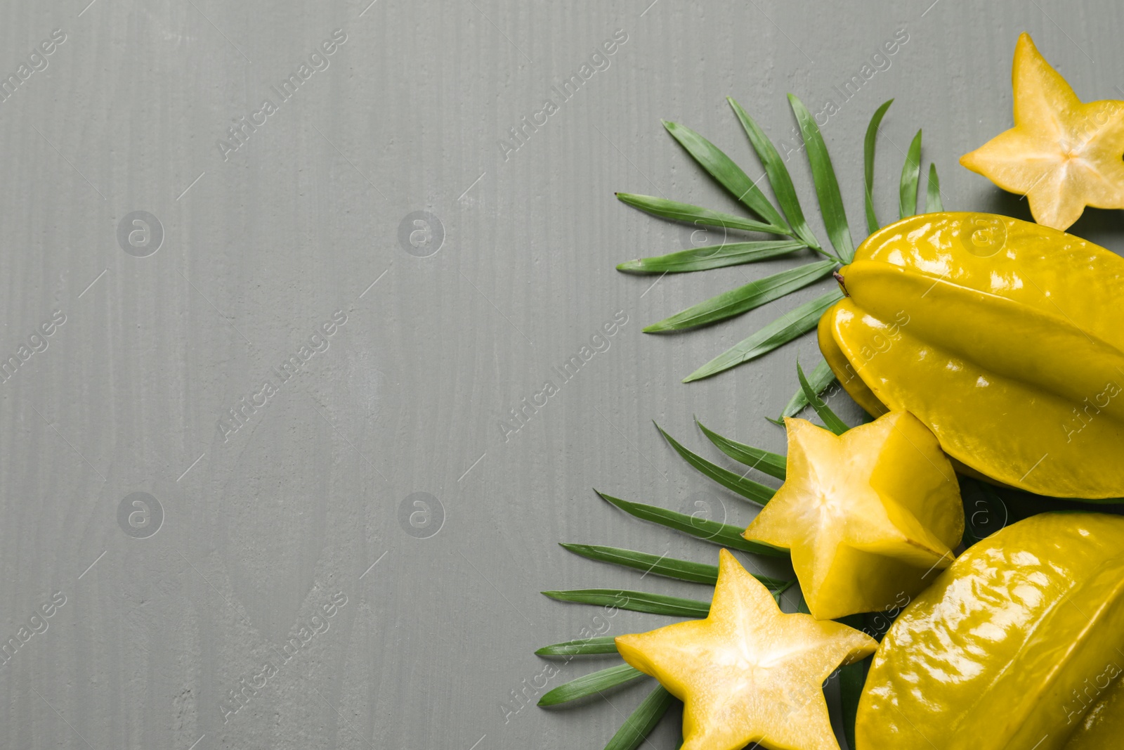 Photo of Delicious carambola fruits on grey wooden table, flat lay. Space for text