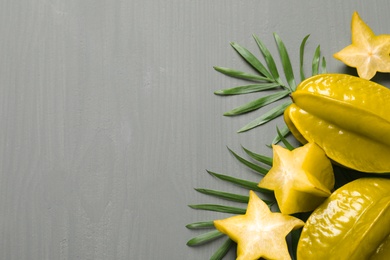 Delicious carambola fruits on grey wooden table, flat lay. Space for text