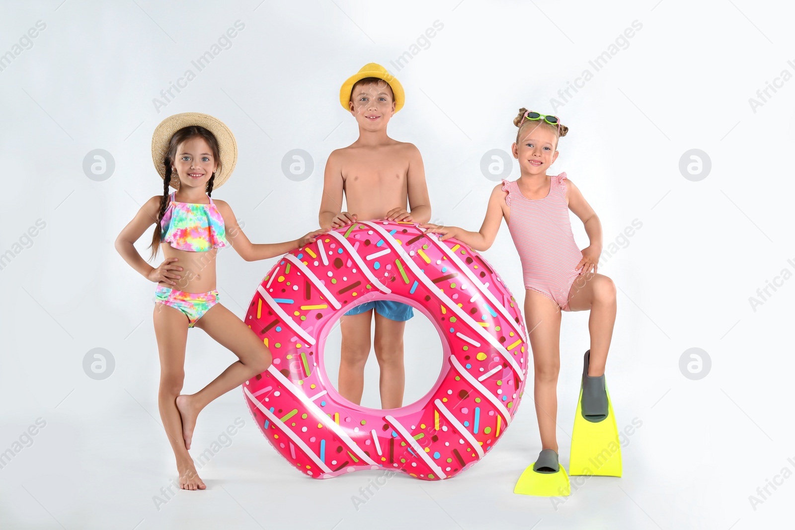 Photo of Cute little children in beachwear with bright inflatable ring on white background